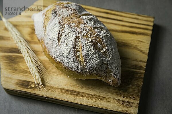 Schönes Sauerteigbrot auf grauem Hintergrund mit getrockneter Weizenblüte