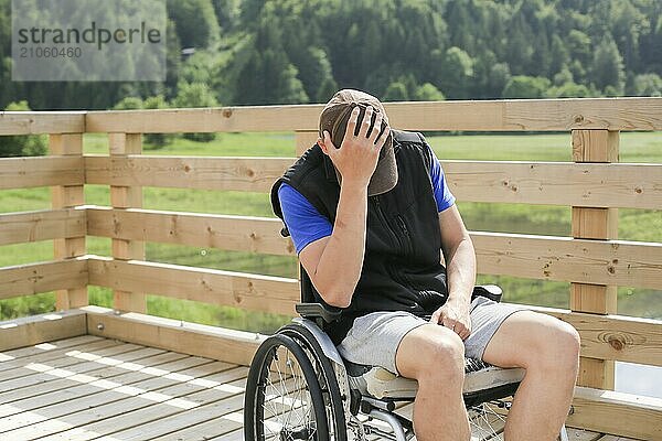 Behinderter junger Mann im Rollstuhl in der Natur  deprimiert  einsam und traurig