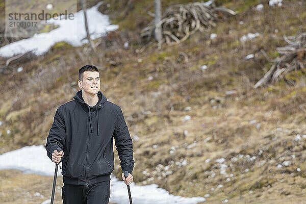 Lässiger und aktiver gesunder Mann beim Wandern in den alpinen Bergen mit Trekkingstöcken