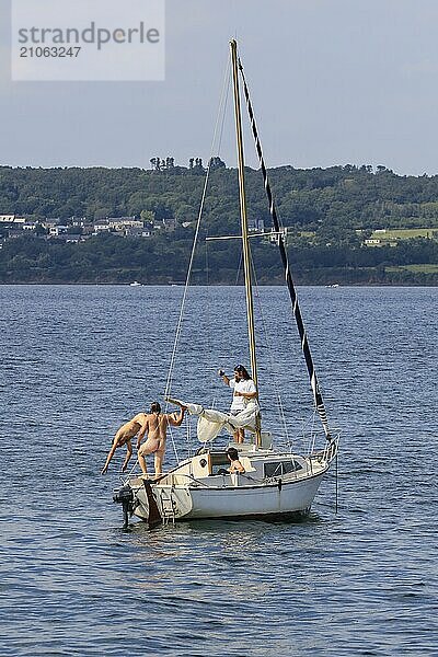 Vier junge Männer auf einem Segelboot  einer springt ins Wasser  Bucht Rade de Brest  Departement Finistere Penn-ar-Bed  Region Bretagne Breizh. Frankreich