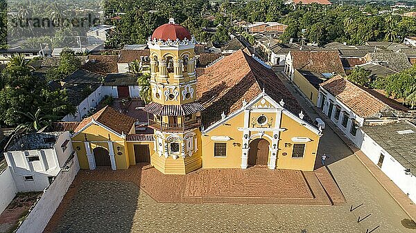 Luftaufnahme der wunderschönen historischen Kirche Santa Barbara (Iglesia de Santa Barbara) Santa Cruz de Mompox im Sonnenlicht mit Fluss und grüner Umgebung  Weltkulturerbe