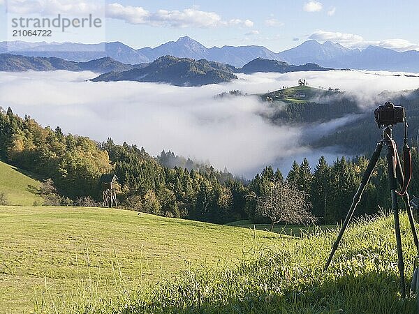 Schöne Sonnenaufgang Landschaft von Saint Thomas Kirche in Slowenien auf dem Hügel in den Morgennebel und Triglav Berg Hintergrund