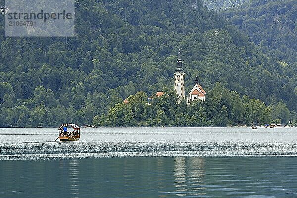 Bleder See mit traditionellem Boot. Schöner Bergsee im Sommer mit kleiner Kirche auf einer Insel mit Schloss auf einer Klippe und Alpen im Hintergrund