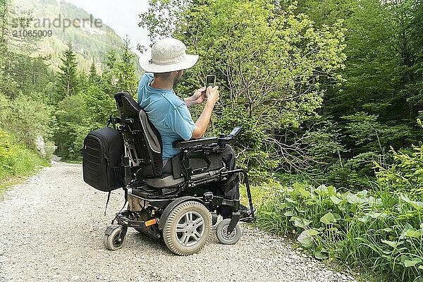 Mann im Rollstuhl benutzt Smartphone Kamera in der Natur