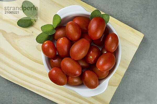 Holzbrett mit Kirschtomaten auf grauem Hintergrund. kulinarischen Hintergrund