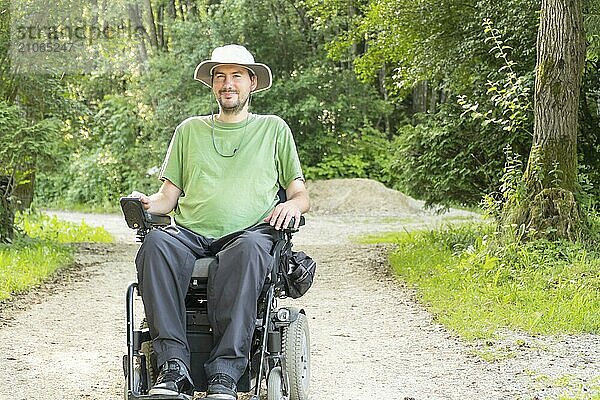 Lachender junger behinderter Mann im Rollstuhl