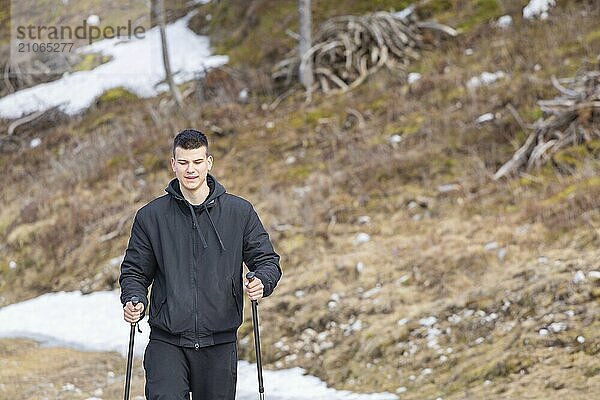 Lässiger und aktiver gesunder Mann beim Wandern in den alpinen Bergen mit Trekkingstöcken