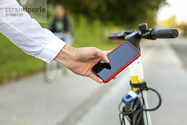 Lässiger Mann  der eine Smartphone App benutzt und einen Elektroroller zum Mieten in der Stadt freischaltet