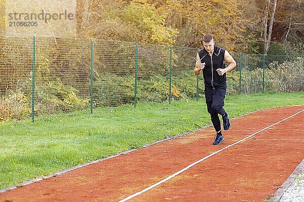 Junger Mann joggt morgens im Freien auf der Laufstrecke