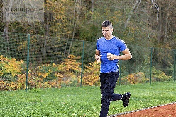 Junger Mann joggt morgens im Freien auf der Laufstrecke