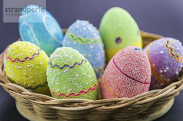 Ostern farbige Eier in einem Korb vor einem trendigen schwarzen Hintergrund. Minimale Ostern Konzept. Osterkarte mit Kopierraum für Text