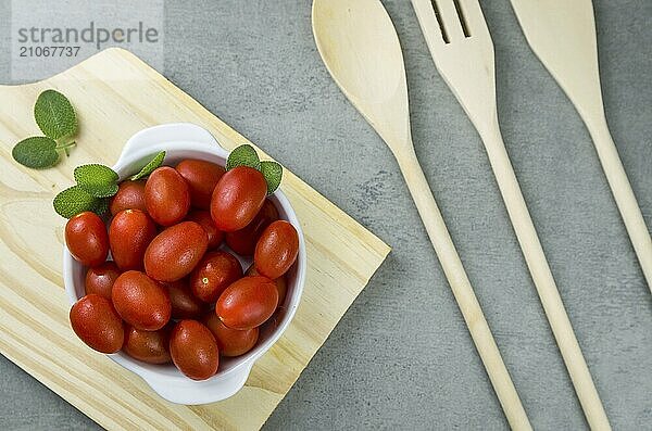 Holzbrett mit Kirschtomaten auf grauem Hintergrund. kulinarischen Hintergrund