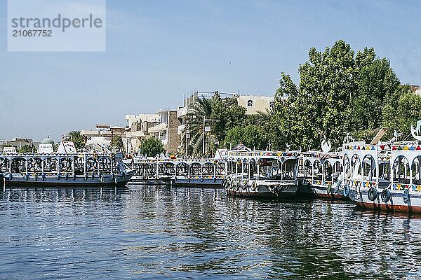 Tauchen Sie ein in die Schönheit von Luxor  während Sie die ruhigen Gewässer des Nils entlangfahren. Dieses atemberaubende Foto fängt den geschäftigen Hafen von Luxor ein  eingerahmt von der Silhouette traditioneller Felukenboote und majestätischer Kreuzfahrtschiffe  die am Hafen angelegt haben. Das Stadtbild bietet eine Kulisse aus leuchtenden Farben und zeitlosem Charme. Erleben Sie die Faszination des Flussufers von Luxor und die Harmonie von Alt und Neu in dieser malerischen Szene. Perfekt für Reisende und Bewunderer von Ägyptens reichem Kulturerbe. Erleben Sie Ägyptens sommerliche Anziehungskraft anhand fesselnder Bilder der Pyramiden  der Sphinx und einer malerischen Nilkreuzfahrt von Assuan nach Luxor. Tauchen Sie ein in die antike Geschichte und lebendige Landschaften