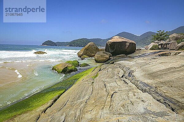 Blick entlang der schönen Küste mit Felsplatten und Bergen im Hintergrund  Picinguaba  Brasilien  Südamerika