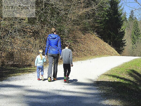 Mutter mit Sohn und Tochter beim Wandern und Spaß haben und zusammen glücklich sein und die Hände halten. Familienausflug in einem Wald im Frühling