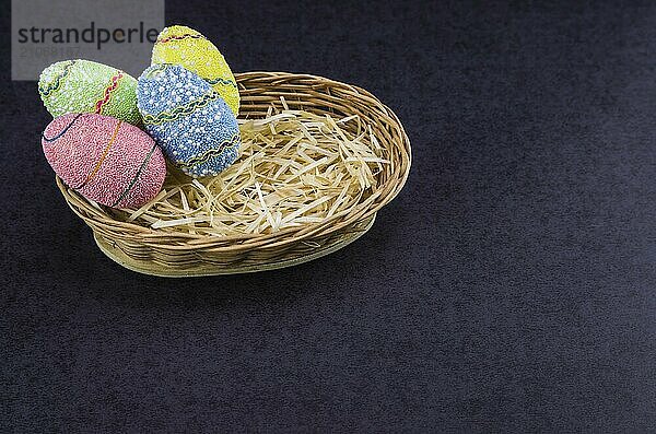 Ostern farbige Eier in einem Korb vor einem trendigen schwarzen Hintergrund. Minimale Ostern Konzept. Osterkarte mit Kopierraum für Text