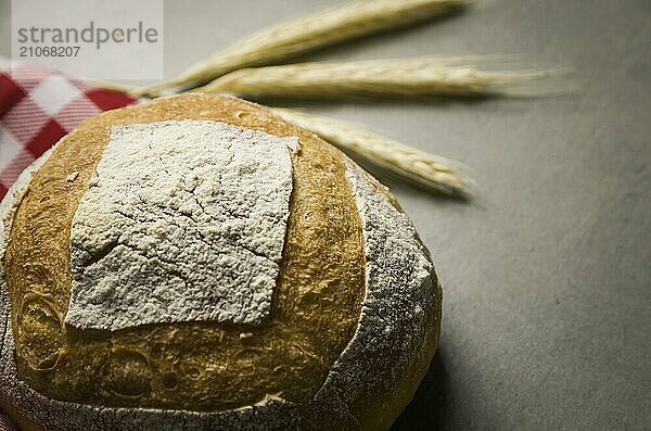 Schönes Sauerteigbrot auf grauem Hintergrund mit getrockneter Weizenblüte