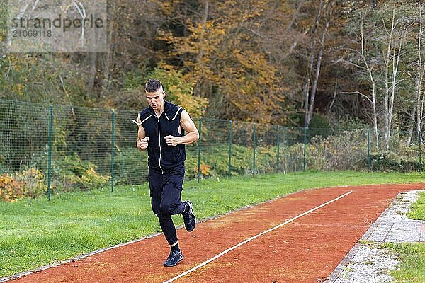 Junger Mann joggt morgens im Freien auf der Laufstrecke