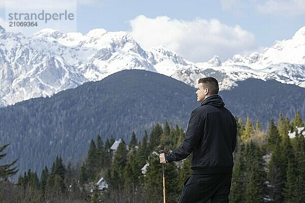 Lässiger und aktiver gesunder Mann beim Wandern in den alpinen Bergen mit Trekkingstöcken