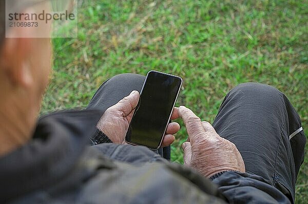 Nahaufnahme des faltigen Fingers eines Mannes  der ein Mobiltelefon berührt