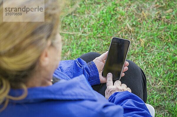 Nahaufnahme des faltigen Fingers einer Frau  die auf ein Handy tippt