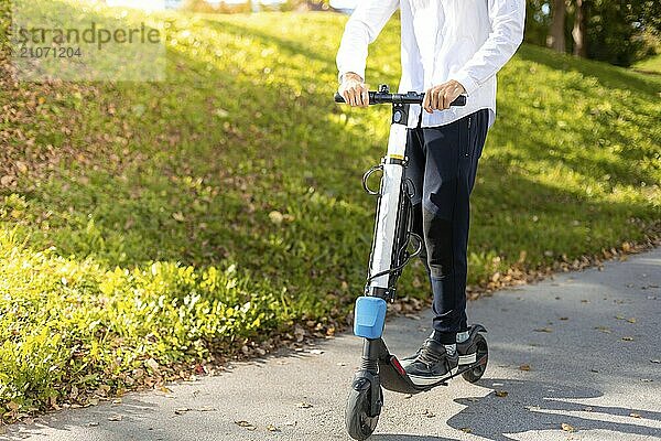 Fröhlicher und lässiger Mann fährt Elektroroller im Stadtpark