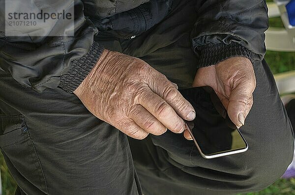 Nahaufnahme des faltigen Fingers eines Mannes  der ein Mobiltelefon berührt