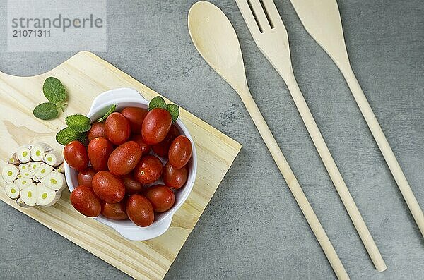 Holzbrett mit Kirschtomaten auf grauem Hintergrund. kulinarischen Hintergrund