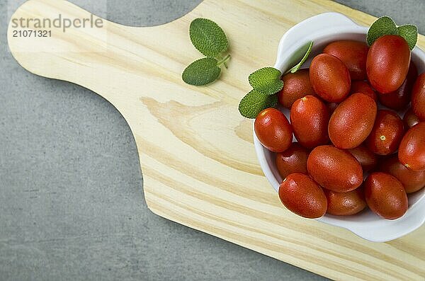 Holzbrett mit Kirschtomaten auf grauem Hintergrund. kulinarischen Hintergrund