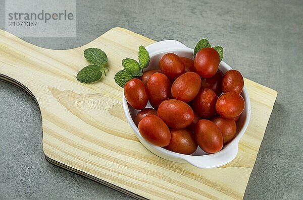 Holzbrett mit Kirschtomaten auf grauem Hintergrund. kulinarischen Hintergrund