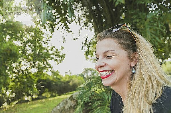 Schöne blonde Frau lächelnd in einem bewaldeten Park