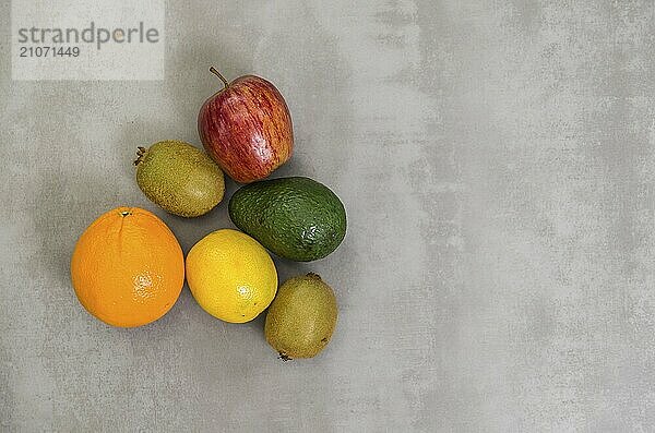 Großes Konzept der gesunden Ernährung  verschiedene Früchte auf grauem Hintergrund  poliertem Beton. Orange  Apfel  Kiwi  Zitrone