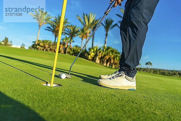 Ausschnittaufnahme eines männlichen Golfspielers  der den Golfball in ein Loch auf dem Golfplatz schlägt