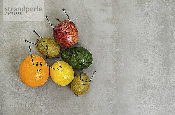 Großes Konzept der gesunden Ernährung  verschiedene Früchte mit glücklichen Gesichtern und Arme nach oben in grauem Hintergrund  poliertem Beton. Orange  Apfel  Kiwi  Zitrone