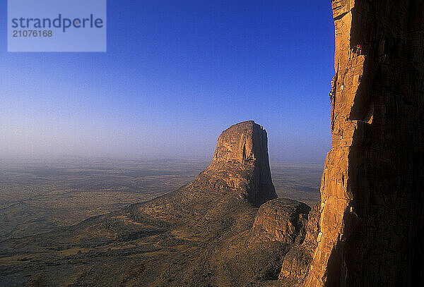 Two men climb one of the sandstone towers that is part of the Hand of Fatima in the Sahara Desert  Mali  West Africa.