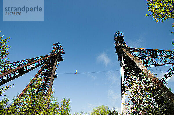 Highliner balancing on tightrope between mine shaft towers  Charleroi  Wallonia  Belgium