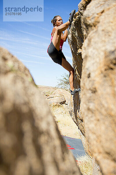 Side view of young woman climbing boulder  Erongo Region  Namibia