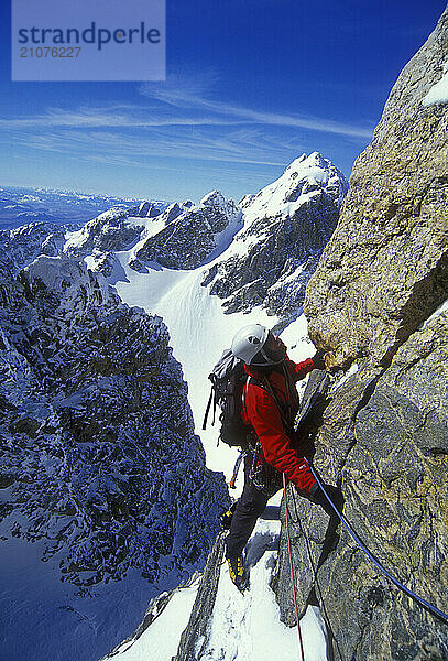 A man plans his next move while climbing in the Teton Range  Grand Teton National Park  Wyoming.