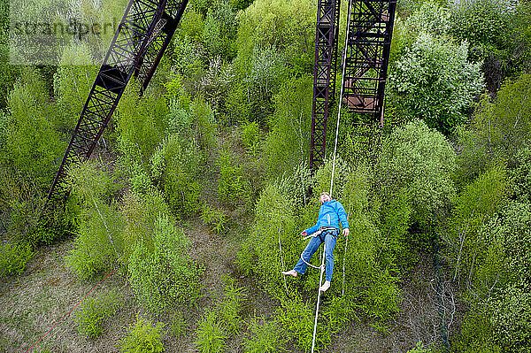 Highliner lying on tightrope on mine shaft tower  Charleroi  Wallonia  Belgium