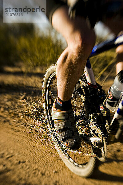 A close up of a man mountain biking on singletrack trail.