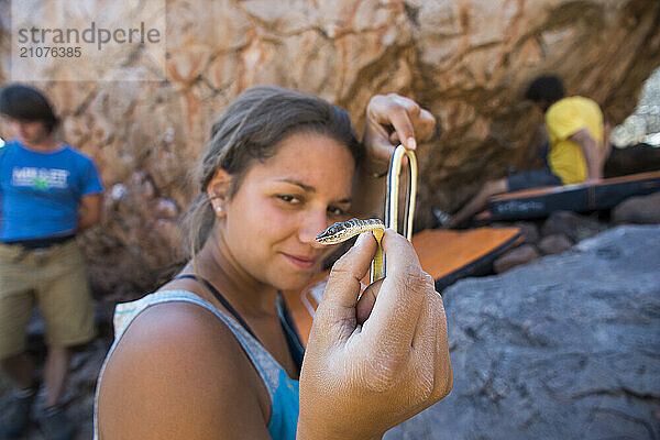 Woman holding small snake and smiling while looking at camera  Otjozondjupa  Namibia