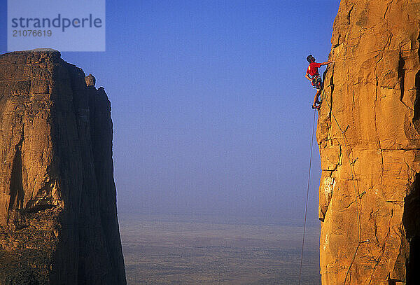 A man rock climbs the sandstone towers known as the Hand of Fatima in the Sahara Desert of Mali  West Africa.