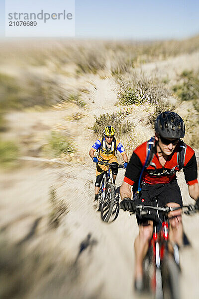 Two men mountain biking desert singletrack.