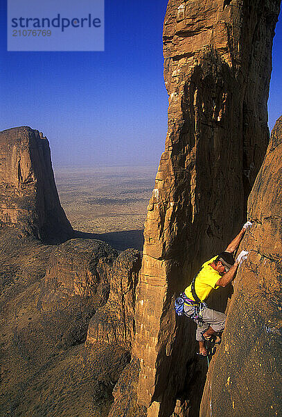 A man rock climbs on the Hand of Fatima in the Sahara Desert  Mali  West Africa.