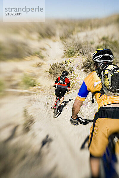 Two men mountain biking desert singletrack.