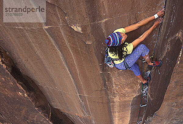 A woman rock climbs on the sandstone walls of Indian Creek  Canyonlands  Utah.