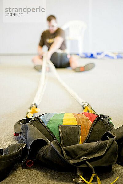 A man sits packing up his parachute in preparation for his next skydive.