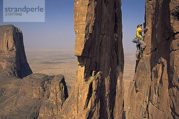 A man rock climbs the sandstone towers known as the Hand of Fatima  in the Sahara Desert of Mali  Africa.