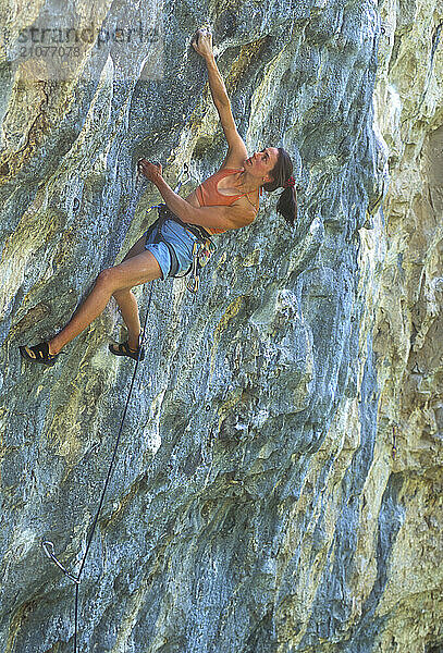 A woman reaches up to a handhold as she rock climbs in Rifle State Park  Colorado.