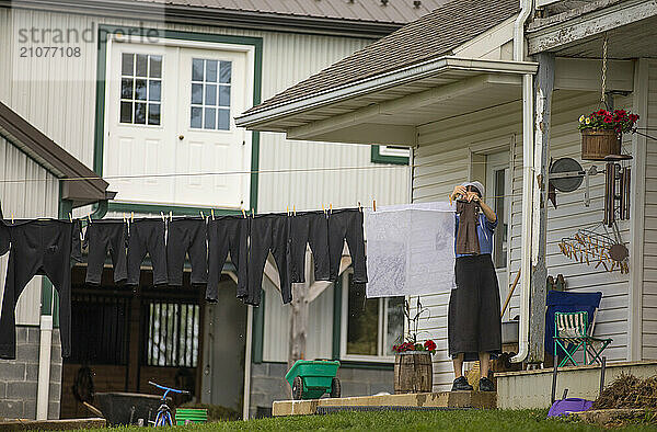 Amish woman hanging laundry outside house  Intercourse  Lancaster County  Pennsylvania  USA